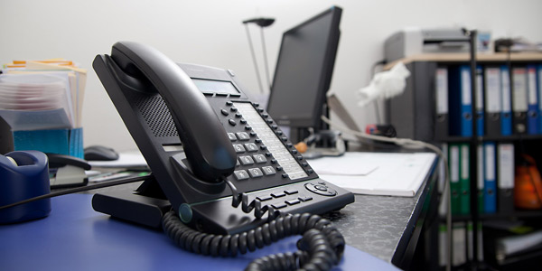 Büro mit Telefon auf Tisch im Vordergrund